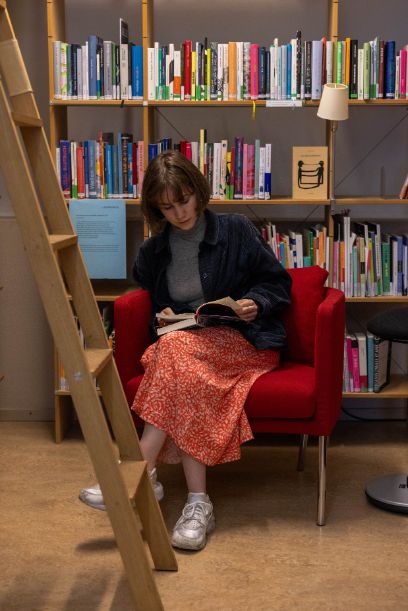 Lena Thomma sitzt in der Bibliothek des Schweizerischen Literaturinstituts und liest ein Buch.