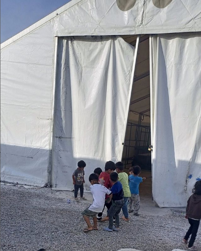 Kinder im Geflüchtetencamp auf Lesbos vor einem Zelt am Seilziehen.