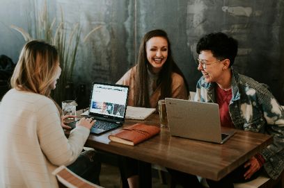 Drei Studierende aktiv und lachend vor dem Laptop am Lernen